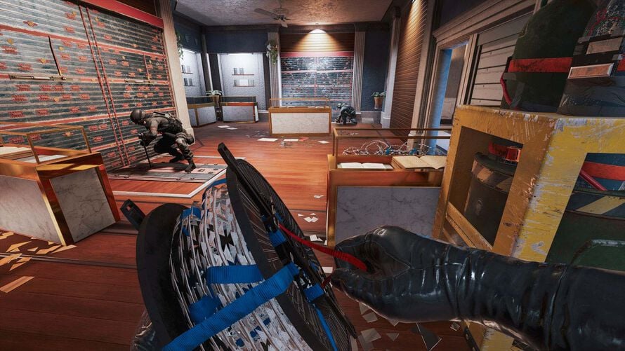 Rainbow Six Siege player setting up barbed wire inside a fortified room with teammates nearby