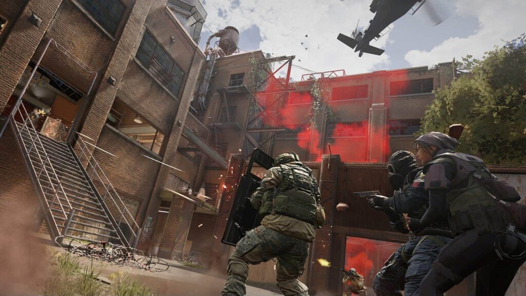 Operators in tactical gear engage in a firefight near a brick building with red smoke and a helicopter overhead in Siege X